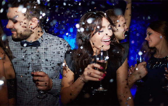 Adults on the dance floor at event reception under silver confetti having fun